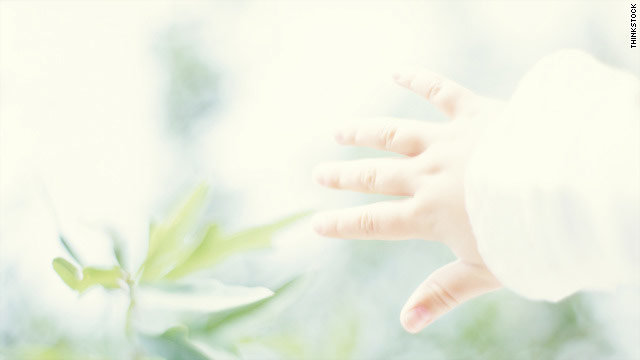 child's hand reaching for flower